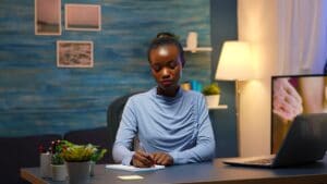 Black business woman writing in notebook working overtime